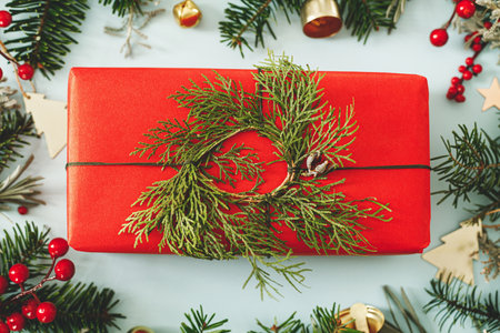 Merry Christmas. Modern Christmas gift with green cedar branches and spruce, red berries,gold ornaments  flat lay on blue background. Stylish christmas wallpaperの写真素材