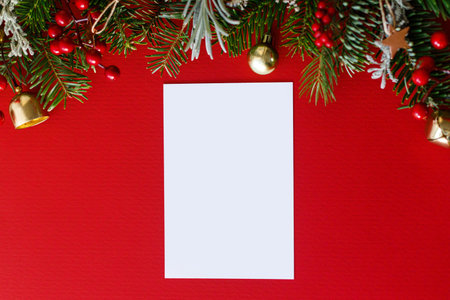 Christmas card flat lay. Modern greeting card mock up with fir branches, red berries and golden ornaments on red background. Empty postcard template, space for text. Merry Christmasの写真素材