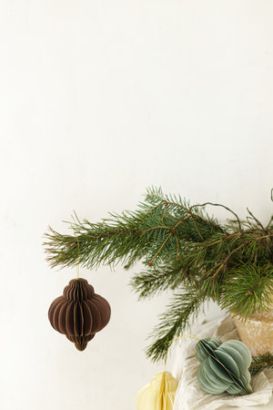 Modern rustic winter bouquet on table in scandinavian room. Stylish christmas paper  ornaments on spruce branches in vase. Christmas home authentic decorの写真素材