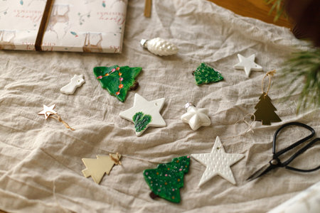 Modern authentic Christmas ornaments. Stylish handmade clay tree, star with scissors and thread on rustic table. Christmas gift decor. Winter handcraft and holiday preparationの写真素材