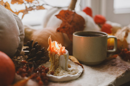 Autumn still life. Warm cup of tea, pumpkins, fall leaves, candle and woolen scarf on windowsill. Autumn hygge. Happy Thanksgivingの写真素材
