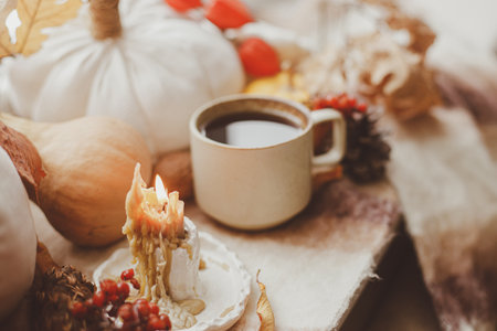 Hello fall. Candle, warm cup of tea, pumpkins, autumn leaves and woolen scarf on windowsill. Autumn hygge still life. Happy Thanksgiving.の写真素材