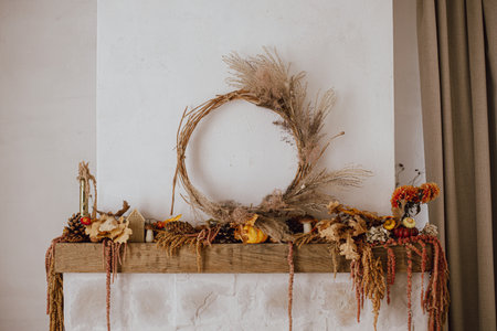 Stylish autumn decor of fireplace mantel in living room. Pumpkins, autumn leaves, wreath, pine cones, candle on rustic wood on fireplace. Fall season decoration. Thanksgiving and Halloweenの写真素材