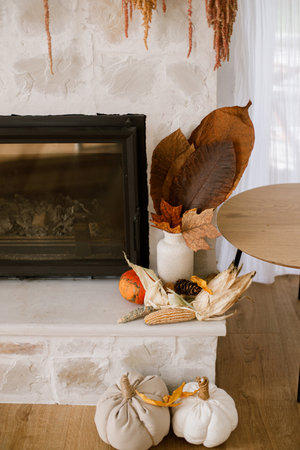 Stylish autumn decor of fireplace in farmhouse  living room. Pumpkins, autumn leaves, pillows at fireside. Fall season decoration. Thanksgiving and Halloweenの写真素材