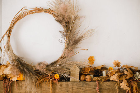 Stylish decoration of fireplace with pumpkins, wreath, autumn leaves, nuts, candle on rustic wood in modern farmhouse living room. Autumn fireplace mantel. Thanksgiving and Halloweenの写真素材