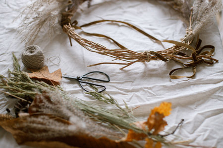 Making stylish autumn wreath. Dried grass, herbs, leaves, ribbon and scissors on rustic table. Details of fall decor and arrangement in home. Thanksgiving and Halloweenの写真素材
