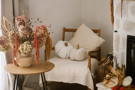 Stylish autumn decor of fireplace in farmhouse  living room. Pumpkins, autumn leaves, pillows at fireside. Fall season decoration. Thanksgiving and Halloweenの写真素材