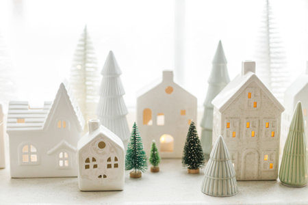 Merry Christmas! Stylish Christmas miniature holiday village with glowing white houses and trees on snowy window. Atmospheric magical scene. Christmas holiday banner.の写真素材