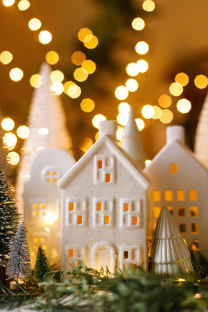 Christmas still life, miniature winter holiday village. Merry Christmas and Happy Holidays! Christmas houses, trees and golden lights bokeh on table with fir branches. Atmospheric magical eveの写真素材