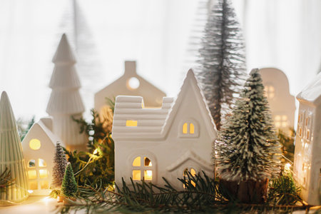 Merry Christmas! Stylish Christmas miniature holiday village with houses, trees and golden lights bokeh on window in evening. Atmospheric magical scene. Christmas holiday banner.の写真素材