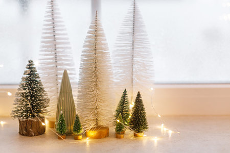 Christmas little snowy trees and golden lights on window. Xmas background. Merry Christmas! Atmospheric Christmas scene, miniature holiday forestの写真素材