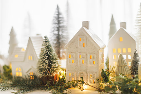 Merry Christmas! Stylish Christmas miniature holiday village with houses, trees and golden lights bokeh on window in evening. Atmospheric magical scene. Christmas holiday banner.の写真素材