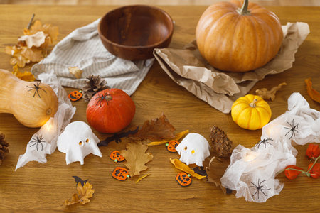 Halloween preparation. Pumpkin and knife, cobweb, ghosts and spiders on table in living room. Making halloween decorations, space for text. Carve a pumpkinの写真素材