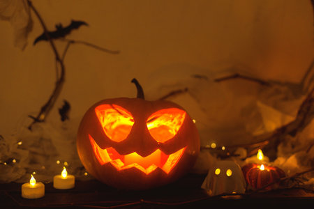 Spooky Jack o lantern pumpkin, glowing ghosts, spiders and bats in evening. Happy Halloween! Atmospheric halloween decor on table, space for text. Trick or treatの写真素材