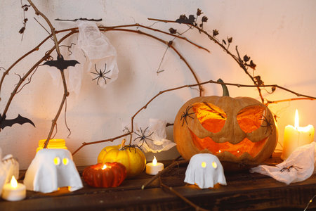 Halloween pumpkin, glowing ghosts, spiders and bats on table. Happy Halloween! Halloween decor with spooky Jack o lantern and candles , space for text. Trick or treatの写真素材
