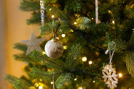 Stylish christmas ornament on tree close up. Beautiful decorated christmas tree with glass snowflake, vintage baubles and golden lights. Winter holidays preparation. Atmospheric magical eveの写真素材