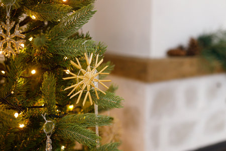 Beautiful decorated christmas tree with straw snowflake, vintage baubles and golden lights. Winter holidays preparation. Atmospheric magical eve. Stylish christmas ornament on tree close upの写真素材