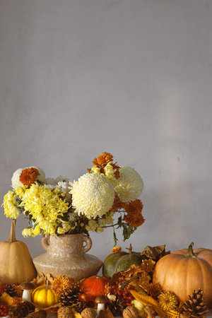 Thanksgiving background. Pumpkins and chrysanthemum in vase, fall leaves, berries and pine cones on table, space for text. Autumn harvest still life. Happy Thanksgiving. Fall bannerの写真素材