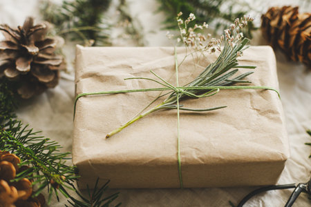 Zero waste Christmas concept. Stylish christmas gifts wrapped in craft paper with green fir branch on rustic table with natural ornaments. Sustainable lifestyle, winter holiday bannerの写真素材