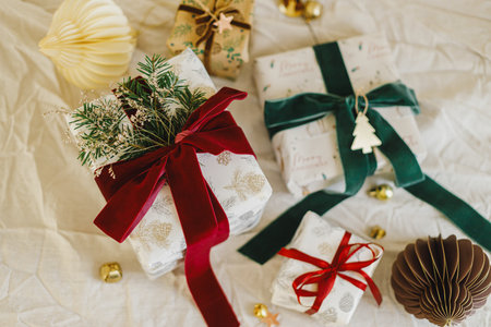 Merry Christmas and Happy Holidays. Stylish christmas gifts with red and green ribbons, fir branches, vintage toy and modern ornaments on rustic table. Wrapped Christmas presents, flat layの写真素材