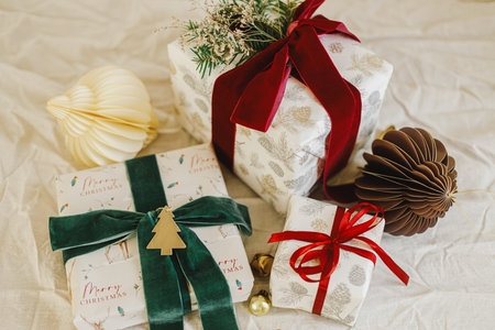 Merry Christmas and Happy Holidays. Stylish christmas gifts with red and green ribbons, fir branches, vintage toy and modern ornaments on rustic table. Wrapped Christmas presents, holiday bannerの写真素材