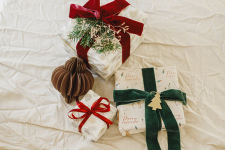 Merry Christmas and Happy Holidays. Stylish christmas gifts with red and green ribbons, fir branches, vintage toy and modern ornaments on rustic table. Wrapped Christmas presents, holiday bannerの写真素材