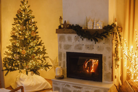 Stylish christmas tree with vintage baubles and golden lights in modern living room with festive decorated fireplace mantel. Festive xmas scandinavian room. Atmospheric magical eveの写真素材