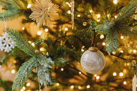Beautiful decorated christmas tree with glass icicle, vintage baubles and golden lights. Winter holidays preparation. Atmospheric magical eve. Stylish christmas ornament on tree close upの写真素材