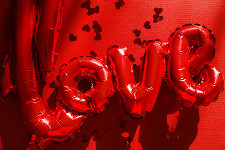 Love flat lay. Happy valentines day. Stylish love word balloon and red hearts confetti on red background. Love backgroundの写真素材