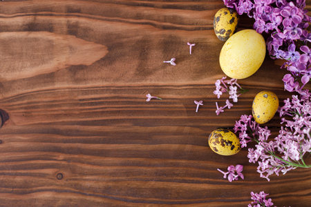 Easter flat lay. Stylish easter eggs and lilac blossom on rustic wooden background, space for text....