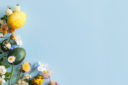 Easter flat lay. Stylish easter eggs and spring flowers on blue background, space for text. Easter modern minimal banner. Season greetings mockupの写真素材