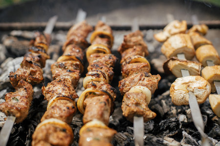 Delicious kebab roasting in fire pit close up. Meat and vegetable bbq grilling in smoke in modern fireplace pit. Summer picnic outdoor. 4 of julyの写真素材