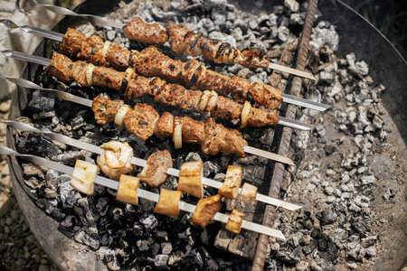 Delicious kebab roasting in fire pit close up. Meat and vegetable bbq grilling in smoke in modern fireplace pit. Summer picnic outdoor. 4 of julyの写真素材