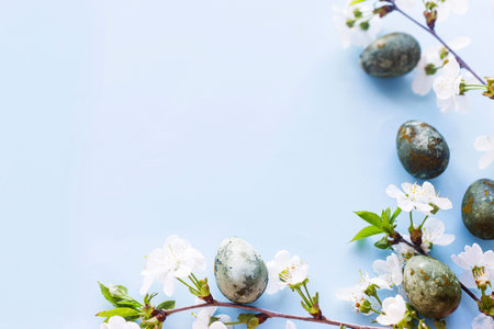 Happy Easter! Easter eggs with cherry blossom flat lay on blue background. Stylish spring template...