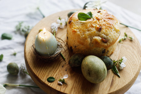 Easter celebration. Stylish green easter eggs, easter bread, candle and cherry blossoms on linen...