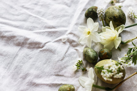 Happy Easter! Stylish natural dyed eggs and spring flowers on linen background flat lay. Holiday...