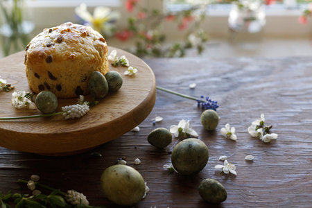 Easter bread, natural dyed eggs and spring flowers on rustic wooden table. Atmospheric authentic...
