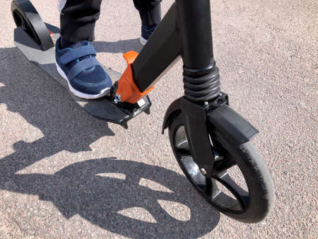 Legs and scooter close-up on asphalt.