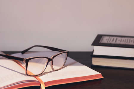 There are glasses on the table next to the books on an open notebook. Space for text, negative...