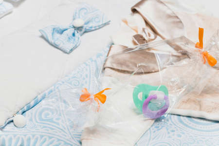 Baby boy pacifier on a blue background in a gift box and baby clothes, postcard. Child birth symbol. Selective focus.の写真素材