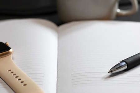 White sheet of paper with a black pen on an office table with a smart watch and a cup of coffee....