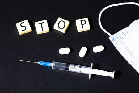 STOP written on blocks on the table next to pills, syringe and medical mask. Flat lay. Medical concept.の写真素材