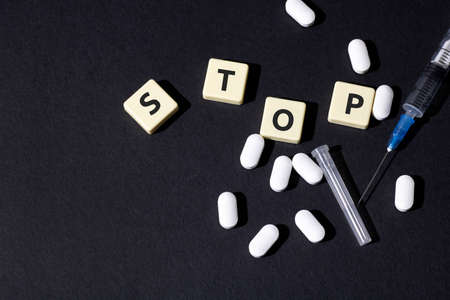 On the table is a syringe, pills and the word stop is written in letters. Place to copy.の写真素材