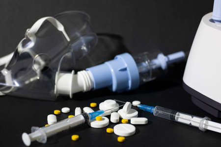 Medicines, syringes, a mask and an apparatus for the administration of drugs by inhalation on a dark background. The concept of health and disease.の写真素材