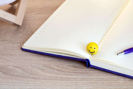 Open blank notebook on a wooden table, vintage tone and yellow emoticonの写真素材