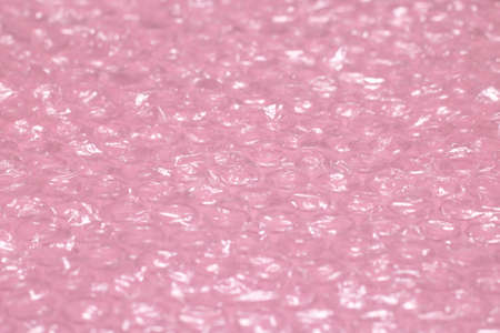 Pink background of polymer packaging material, layers of smooth and bubble polyethylene, wrap.