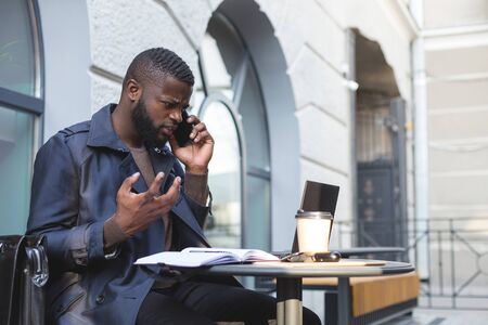 African american bussines man having a heated arguement with colleague over the phone.の写真素材