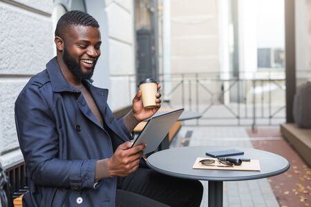 Young entrepreneur enjoying his cup of coffee while checking stock on his tab.の写真素材