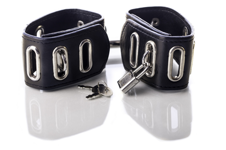 Leather handcuffs symbollic of the bondage sex fetish and sexual role play. Image isolated against...