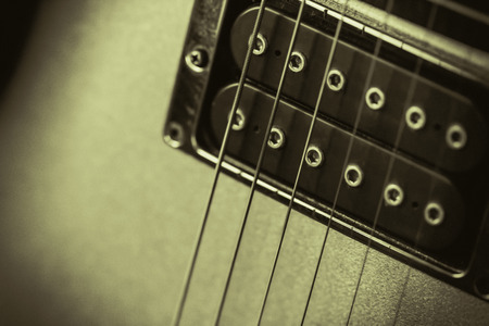Black humbucker pickup on a gold guitar. Retro monochrome image with a soft feel. Nice background or...